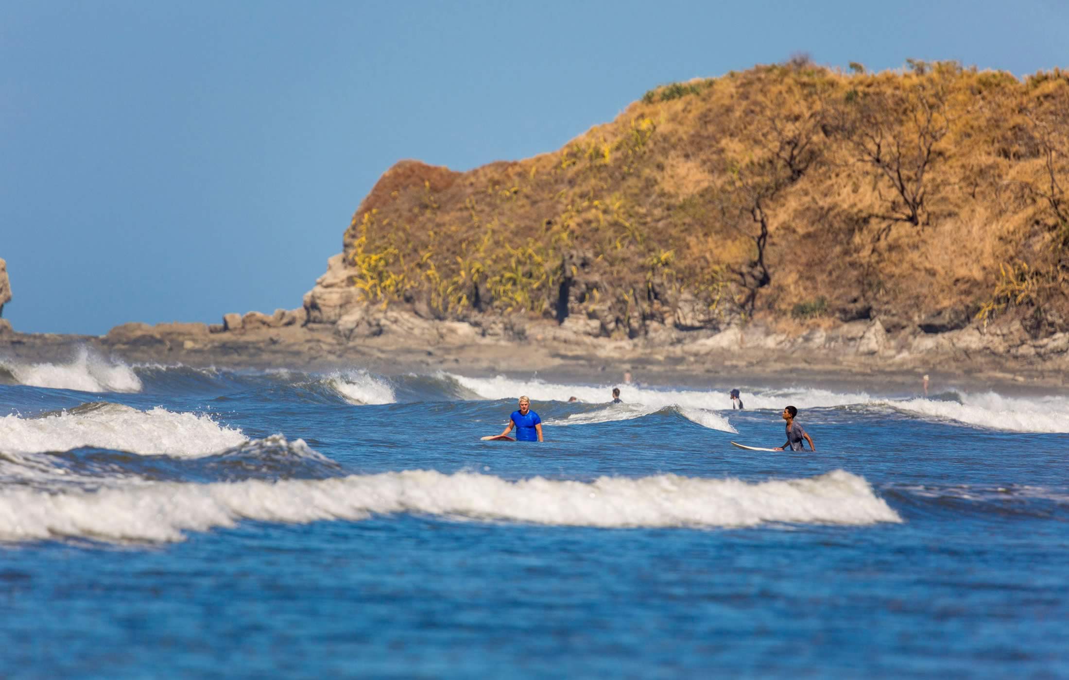 Photograph of several people surfing, as captured from the Mango Property Management website
