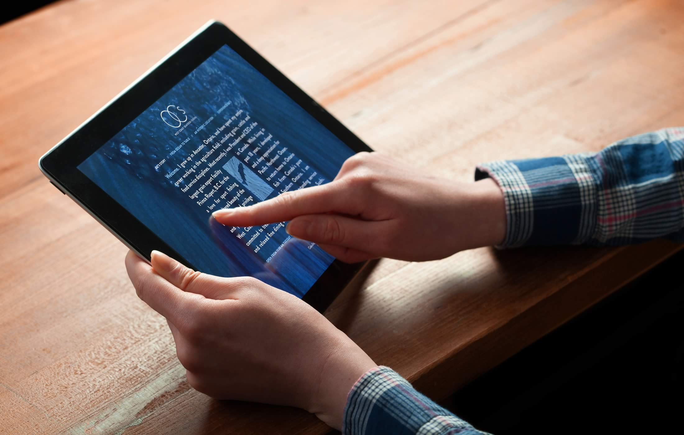 Closeup of a person interacting with the OC’s West Coast website on their tablet